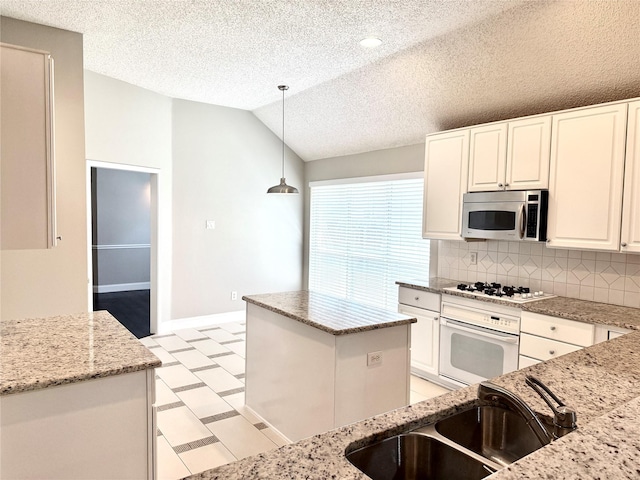 kitchen featuring white appliances, a sink, light floors, vaulted ceiling, and baseboards