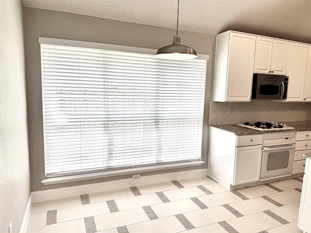 kitchen featuring white appliances, baseboards, white cabinets, a textured ceiling, and tasteful backsplash
