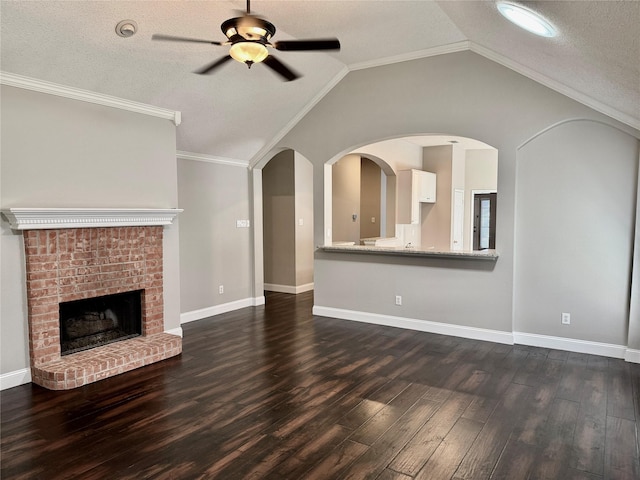 unfurnished living room with ceiling fan, dark wood finished floors, a brick fireplace, vaulted ceiling, and a textured ceiling