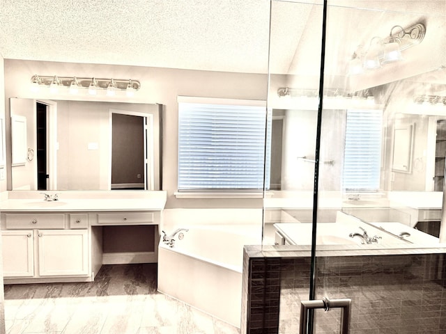 bathroom featuring a bath, vanity, marble finish floors, and a textured ceiling