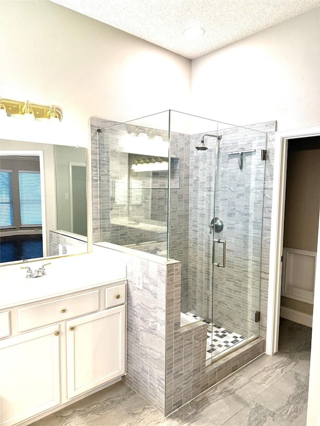 full bath featuring a textured ceiling, a stall shower, vanity, and marble finish floors