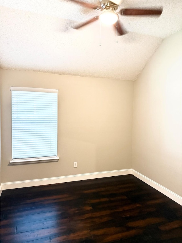 unfurnished room featuring dark wood-style flooring, vaulted ceiling, a textured ceiling, baseboards, and ceiling fan
