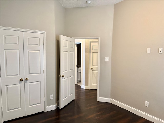 hall with baseboards, dark wood-style floors, and a textured ceiling