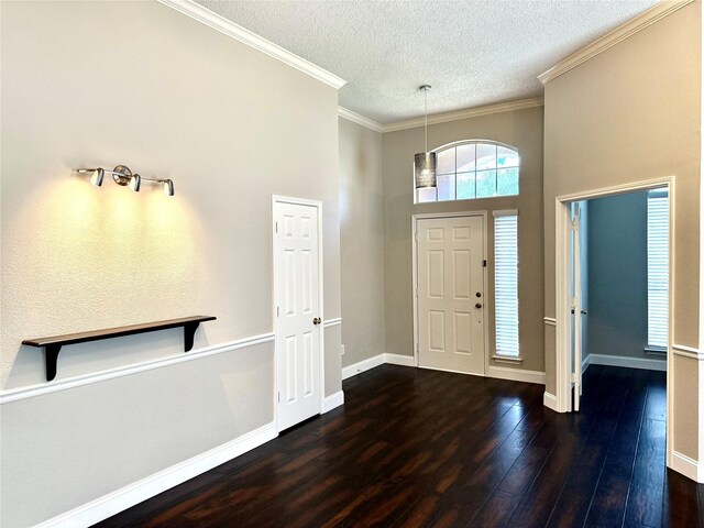 foyer with a textured ceiling, wood finished floors, ornamental molding, baseboards, and a high ceiling
