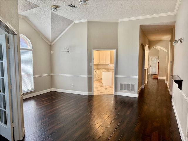 spare room with arched walkways, vaulted ceiling, wood-type flooring, a textured ceiling, and ornamental molding