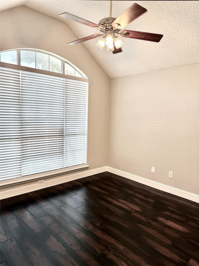 spare room featuring lofted ceiling, a textured ceiling, dark wood-type flooring, a ceiling fan, and baseboards