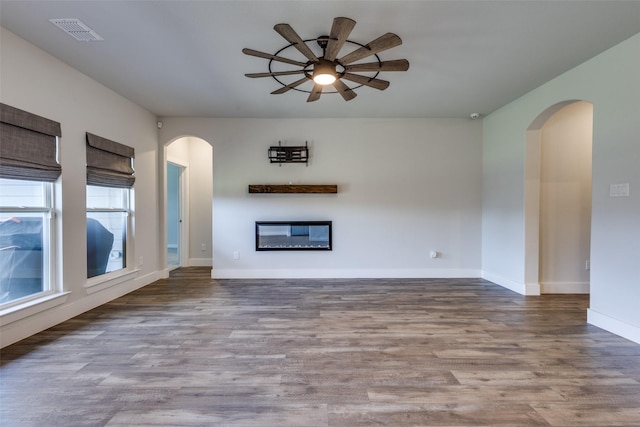 611 Kyle Dr, Tioga, TX 76271 - unfurnished living room with a ceiling fan, arched walkways, wood finished floors, and a glass covered fireplace