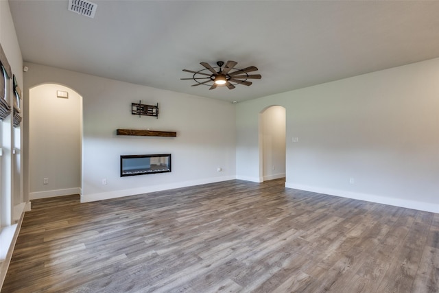 611 Kyle Dr, Tioga, TX 76271 - unfurnished living room with arched walkways, a glass covered fireplace, a ceiling fan, and wood finished floors