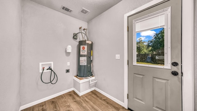 washroom featuring hookup for an electric dryer, electric water heater, hookup for a washing machine, wood finished floors, and baseboards