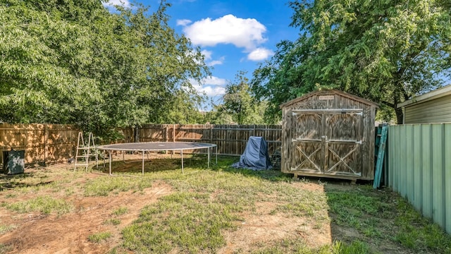 fenced backyard with a storage unit, an outbuilding, and a trampoline