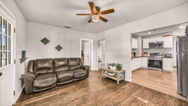 living room with ceiling fan, wood finished floors, and baseboards