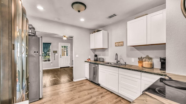 kitchen featuring appliances with stainless steel finishes, a sink, light wood-style flooring, white cabinetry, and recessed lighting