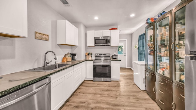 kitchen featuring stainless steel appliances, a sink, light wood-type flooring, white cabinets, and recessed lighting