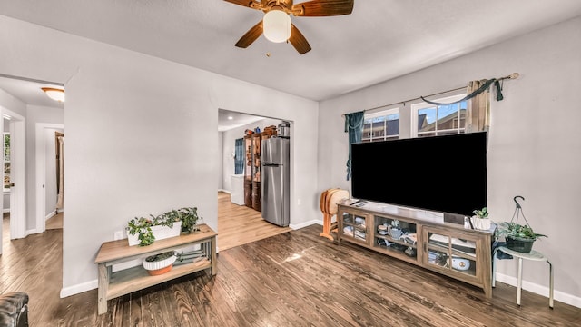 living area featuring wood finished floors, baseboards, and a ceiling fan