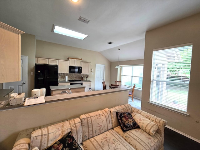 10908 Brandenberg Dr, Frisco, TX 75035 - kitchen with black appliances, lofted ceiling, tasteful backsplash, a peninsula, and pendant lighting