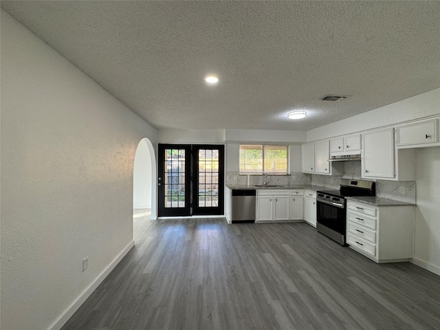 1029 Fox River Ln, Fort Worth, TX 76120 - kitchen with appliances with stainless steel finishes, a sink, a textured ceiling, baseboards, and arched walkways