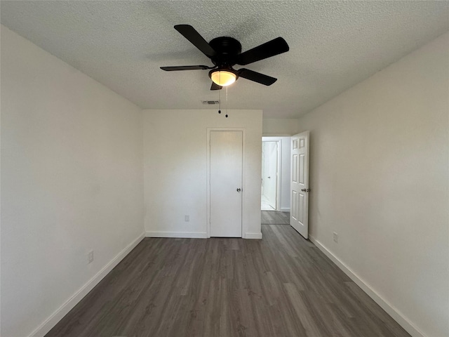 1029 Fox River Ln, Fort Worth, TX 76120 - unfurnished bedroom featuring dark wood-style floors, baseboards, a textured ceiling, and ceiling fan