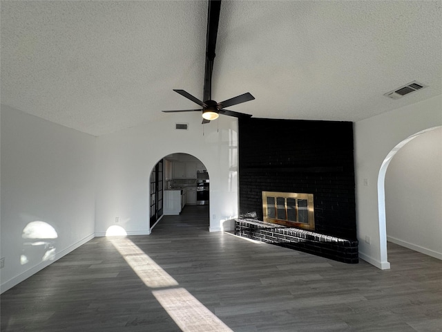 1029 Fox River Ln, Fort Worth, TX 76120 - unfurnished living room with arched walkways, a textured ceiling, a ceiling fan, vaulted ceiling, and a brick fireplace