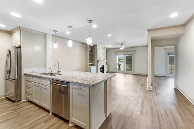 8511 Westover Ct Unit 235, Granbury, TX 76049 - kitchen featuring stainless steel appliances, a sink, a ceiling fan, light wood-type flooring, and a fireplace