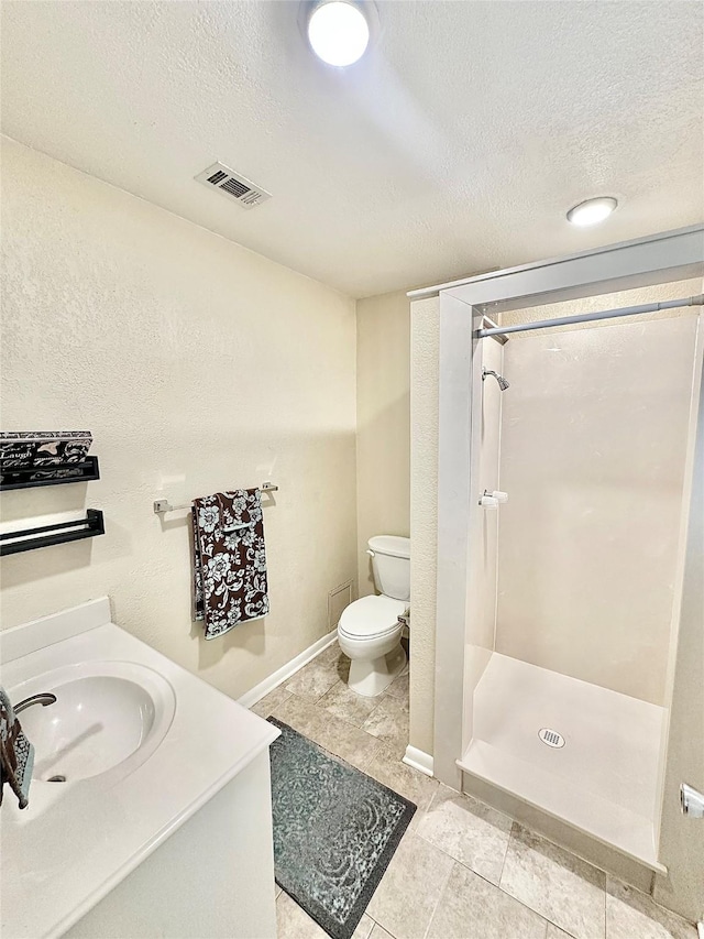 3317 Hummingbird, Denton, TX 76209 - bathroom featuring a textured ceiling, a shower stall, toilet, tile patterned flooring, and vanity