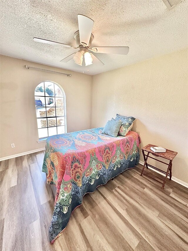 3317 Hummingbird, Denton, TX 76209 - bedroom featuring wood finished floors, a textured ceiling, ceiling fan, and baseboards