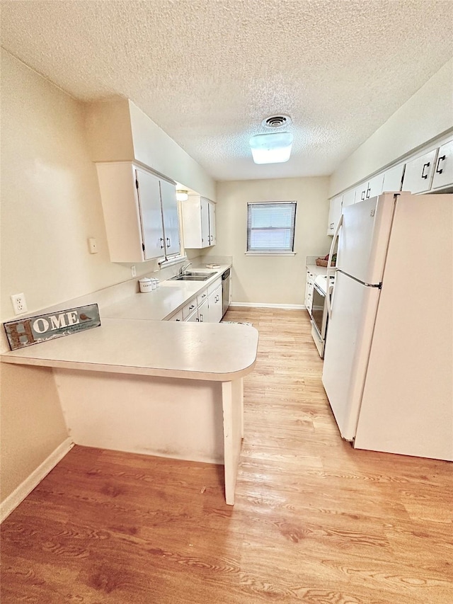 1008 Sierra Dr, Denton, TX 76209 - kitchen featuring freestanding refrigerator, light countertops, light wood-style floors, a peninsula, and baseboards