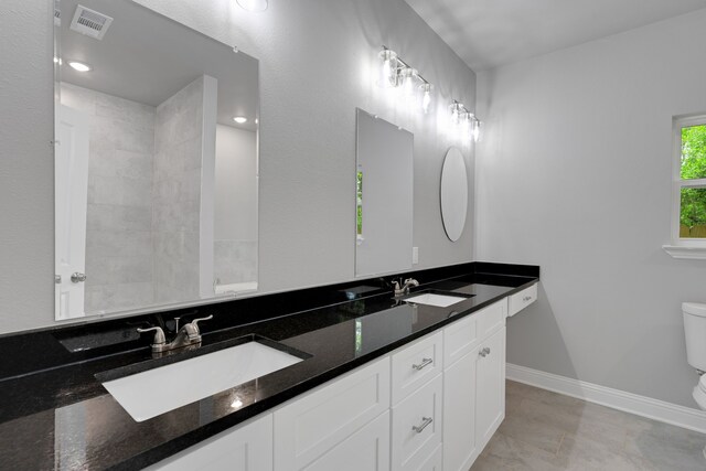 1729 Foster Dr, Arlington, TX 76012 - bathroom featuring toilet, double vanity, and baseboards