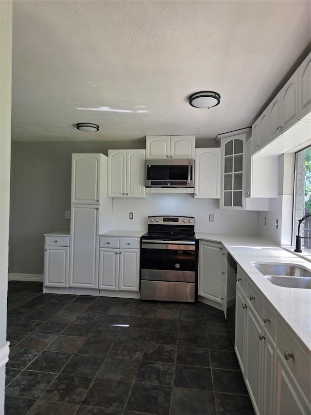 5501 Miami Dr, Rowlett, TX 75088 - kitchen featuring stainless steel appliances, a sink, white cabinetry, baseboards, and glass insert cabinets