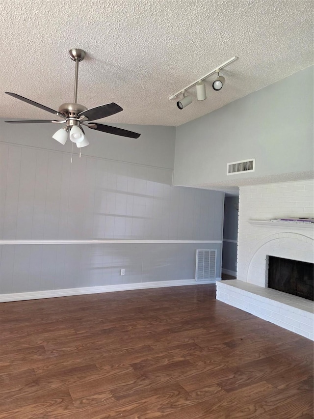 5501 Miami Dr, Rowlett, TX 75088 - unfurnished living room with track lighting, wood finished floors, a ceiling fan, a textured ceiling, and a fireplace