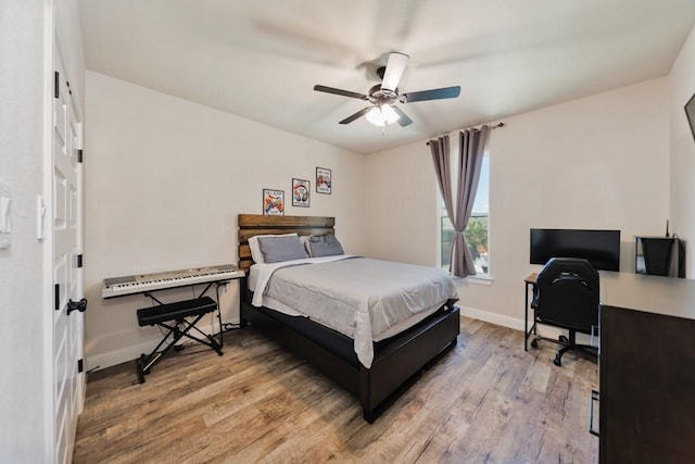 bedroom with light wood-style floors, baseboards, an office area, and a ceiling fan