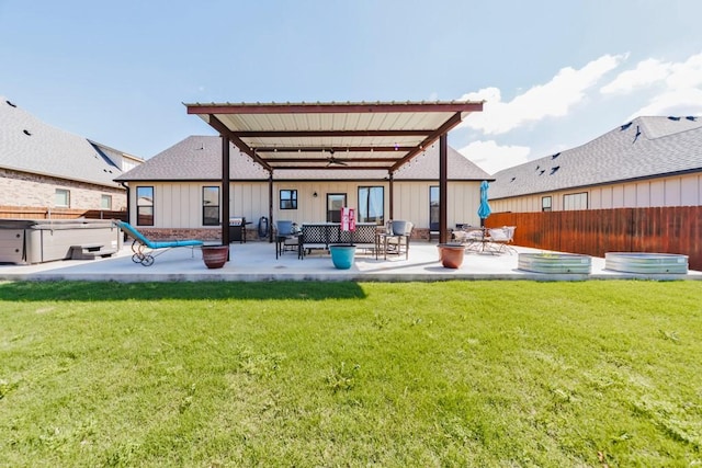 back of property with ceiling fan, a patio area, board and batten siding, a hot tub, and an outdoor living space