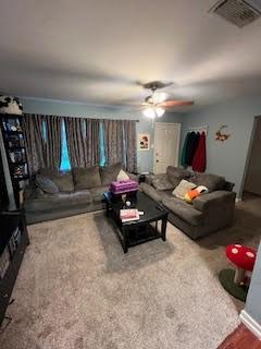 carpeted living area with a ceiling fan