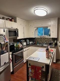 214 Pecos St, Garland, TX 75041 - kitchen featuring stainless steel appliances, white cabinetry, dark wood finished floors, and backsplash