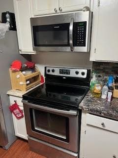 214 Pecos St, Garland, TX 75041 - kitchen with stainless steel appliances, white cabinetry, and wood finished floors
