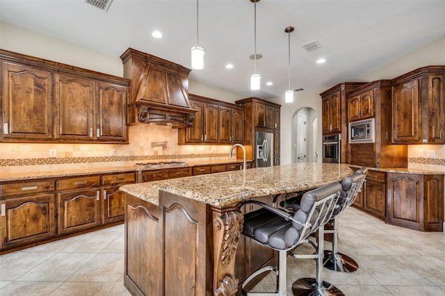 kitchen with stainless steel appliances, custom exhaust hood, arched walkways, light tile patterned flooring, and backsplash