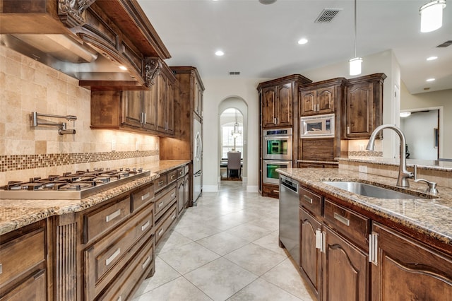 kitchen with stainless steel appliances, a sink, arched walkways, decorative backsplash, and recessed lighting