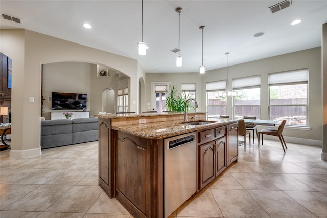 kitchen with a sink, dishwasher, light stone counters, arched walkways, and light tile patterned floors