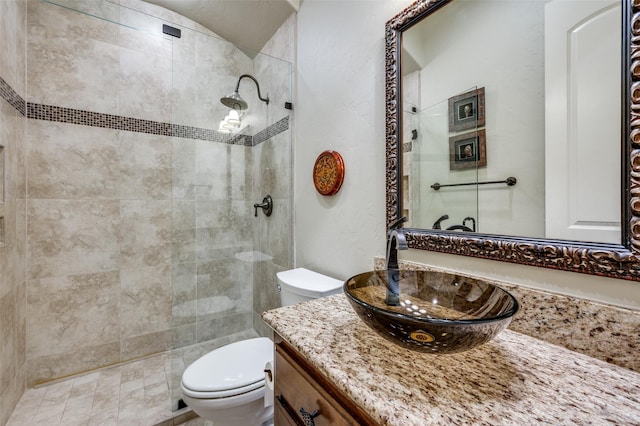 full bathroom with toilet, a tile shower, and vanity