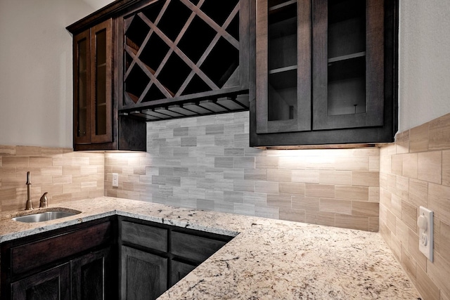 1116 Lake Hills Trl, Roanoke, TX 76262 - kitchen with a sink, glass insert cabinets, decorative backsplash, light stone countertops, and dark brown cabinets
