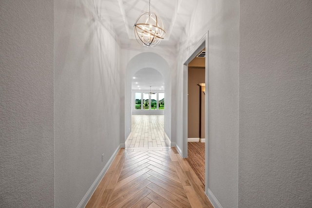 1116 Lake Hills Trl, Roanoke, TX 76262 - corridor featuring arched walkways, a textured wall, a chandelier, light wood-style flooring, and baseboards