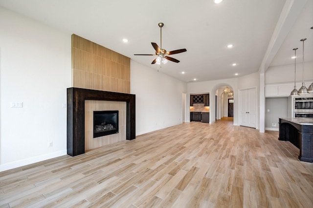 1116 Lake Hills Trl, Roanoke, TX 76262 - unfurnished living room with a fireplace, arched walkways, ceiling fan, light wood-style floors, and recessed lighting