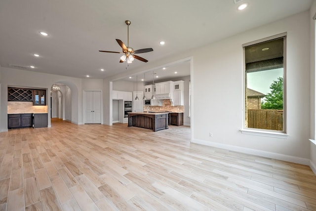 1116 Lake Hills Trl, Roanoke, TX 76262 - unfurnished living room with arched walkways, ceiling fan, light wood-type flooring, baseboards, and recessed lighting