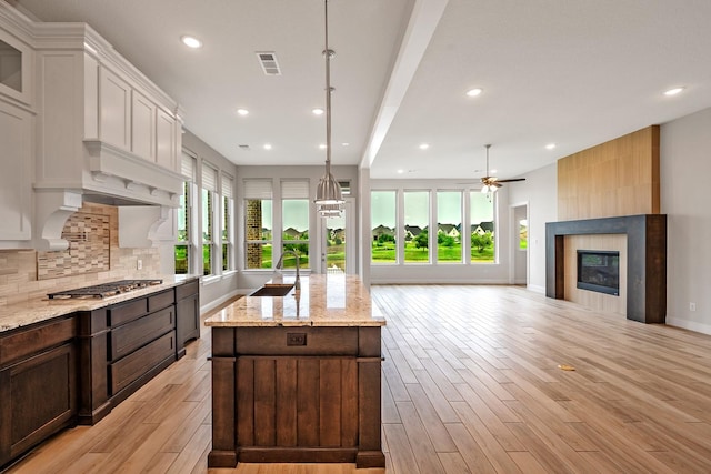 1116 Lake Hills Trl, Roanoke, TX 76262 - kitchen featuring stainless steel gas stovetop, plenty of natural light, a kitchen island with sink, a tiled fireplace, and recessed lighting