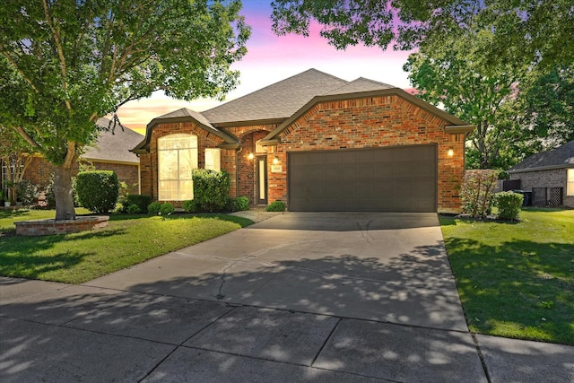 view of front of home featuring a front yard, driveway, a garage, brick siding, and roof with shingles