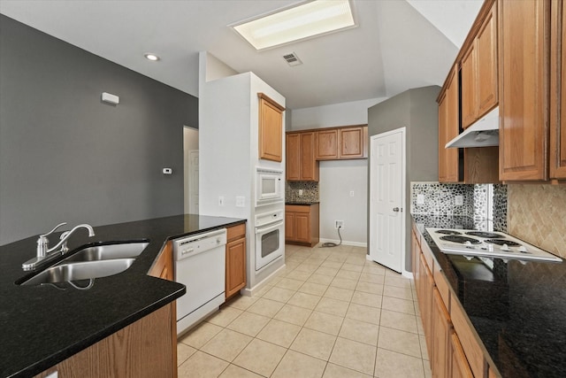 kitchen with a sink, white appliances, under cabinet range hood, decorative backsplash, and light tile patterned floors