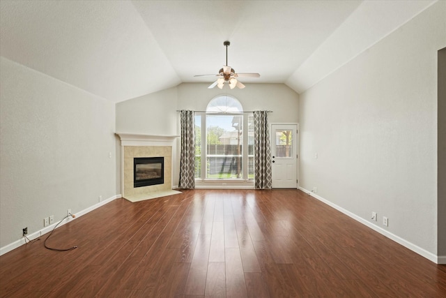unfurnished living room with a ceiling fan, dark wood-type flooring, a tiled fireplace, lofted ceiling, and baseboards