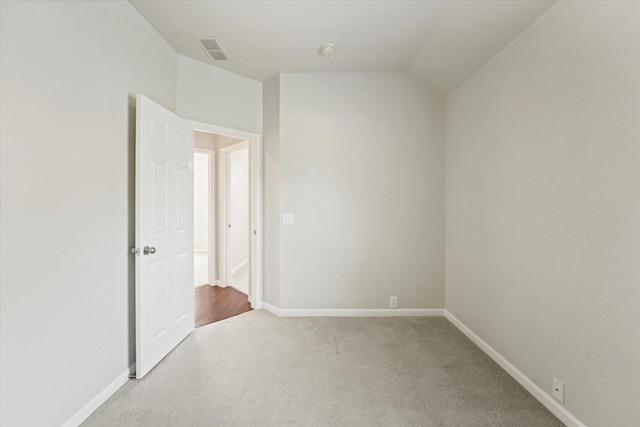 empty room with light colored carpet, baseboards, lofted ceiling, and a smoke detector