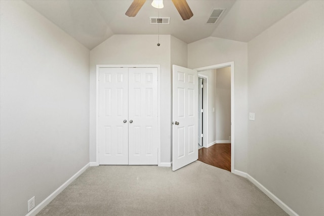 unfurnished bedroom with carpet, baseboards, a closet, vaulted ceiling, and a ceiling fan