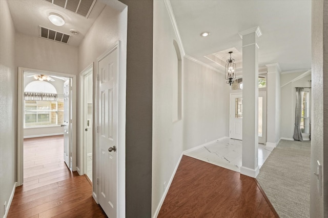 corridor featuring healthy amount of natural light, ornamental molding, ornate columns, wood finished floors, and baseboards