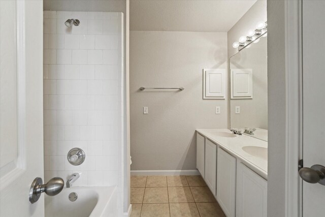 bathroom with tile patterned flooring, washtub / shower combination, double vanity, and baseboards